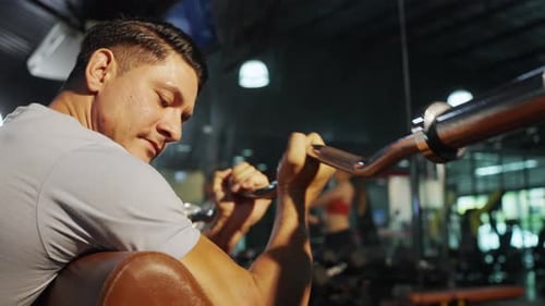 4K Kaukasischer Mann macht Krafttraining beim Heben der Langhantel im Fitnessstudio