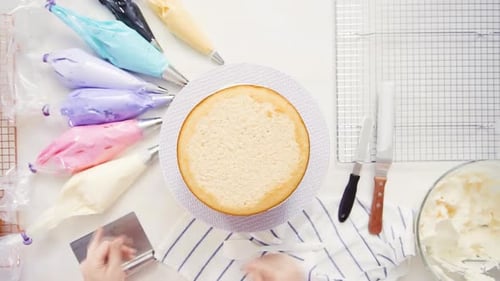 Étape par étape. Vue de dessus. Un chef pâtissier superpose des couches de gâteau avec du glaçage à la crème au beurre entre les deux