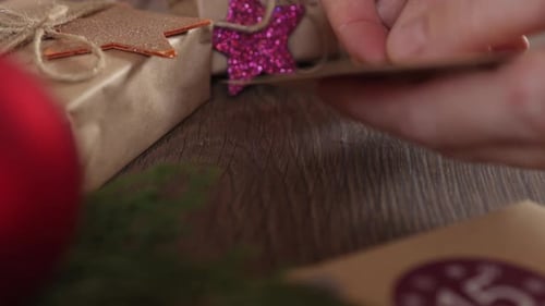 Hands Adding Tag to Christmas Gift