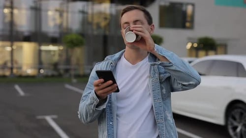 Man Drinking Coffee in City Using Smartphone