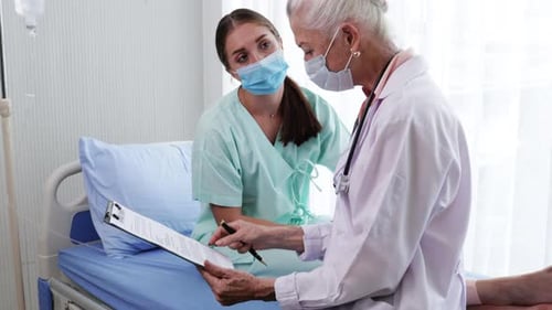 Senior Doctor Consults Patient in Hospital Room