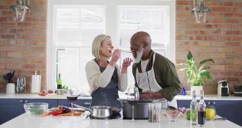 Couple Cooking and Tasting Food in Sunny Kitchen