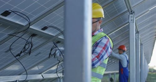 Travailleurs connectant les fils des panneaux solaires