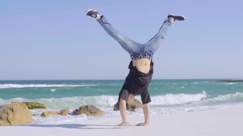 Young Strong Man Showing Impressive Strength Doing a Handstand on the Beach