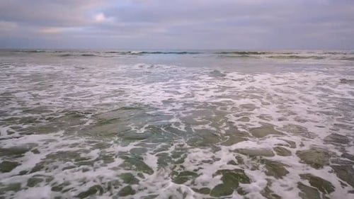 Slowly flying out into the ocean over rolling waves