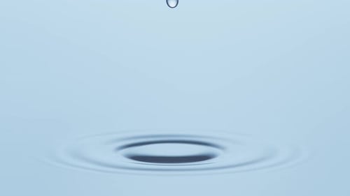 Water Droplets Create Ripples on Blue Surface