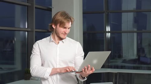 Portrait of Businessman in Office with Laptop Computer.