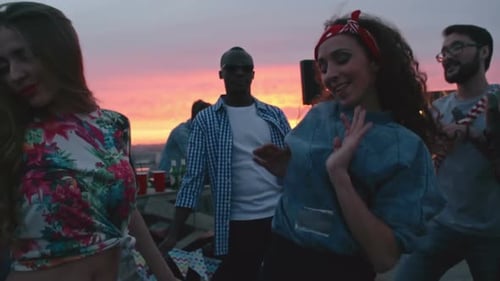 Friends Dancing at Rooftop Party at Sunset