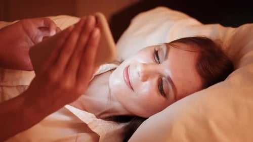Woman Using Smartphone in Bed at Night