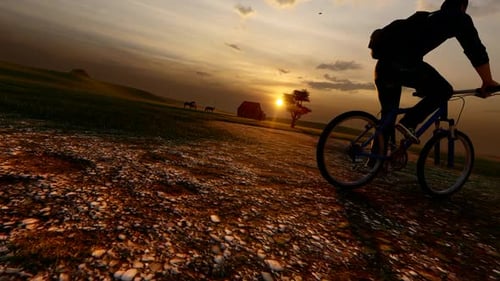 Biker Riding Through Rural Landscape at Sunset