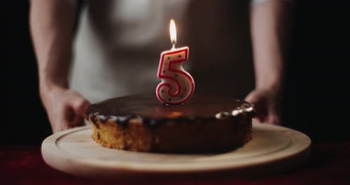 Birthday Cake with Lit Number Candle Being Held