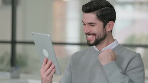 Portrait of Young Man Celebrating on Tablet in Office