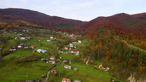Aerial View of a Village Rural Area with Small Houses Between Autumn Mountain Hills Covered with