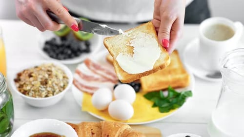 Woman Spreads Butter on Toast at Breakfast