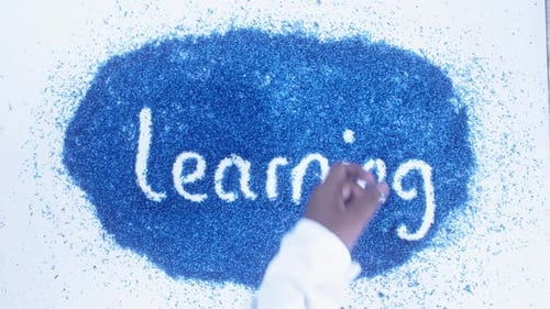 Une main sud-asiatique écrit sur l'apprentissage bleu