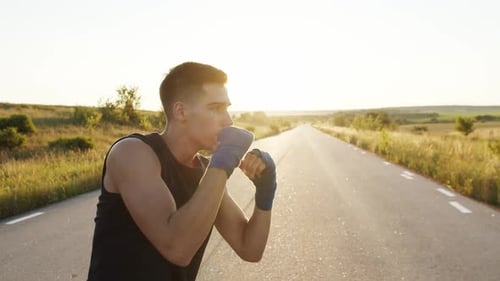 Young Man Boxing on Road at Sunrise