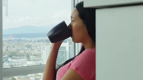 Woman Sips Coffee with a City View