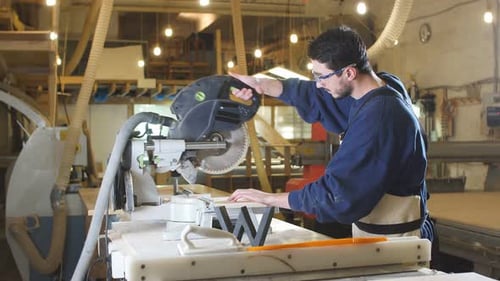 Man Cuts Wood with Power Saw in Workshop