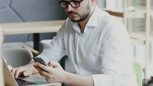 Freelancer in Formal Clothes Sitting in Cafe with Personal Computer and Using Telephone
