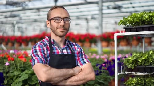 Confident Man in Greenhouse Surrounded by Flowers