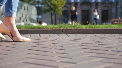 Female Legs in High Heels Shoes Walking Through Urban Street. Feet of Young Woman in High-heeled