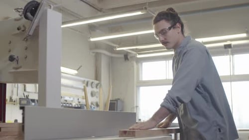 Caucasian Woodworker Smoothing Wood Board on Jointer at Workshop