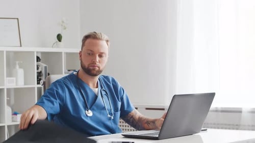 Professional medical doctor is working in hospital office using computer.