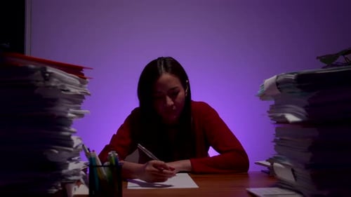 Young Woman Working Late at Desk With Paperwork