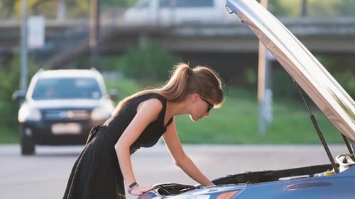 Young Woman Opens Car Hood Looking Confused