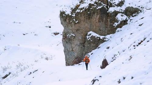 Hiker trekking across a snowy mountain landscape