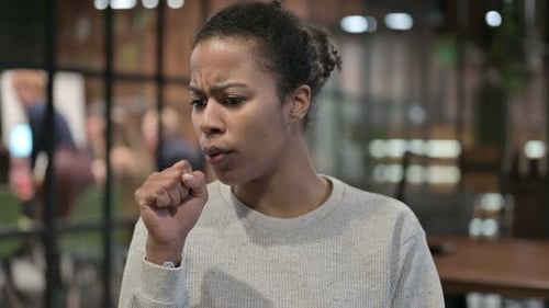 Woman Coughing into Fist in Gray Sweater