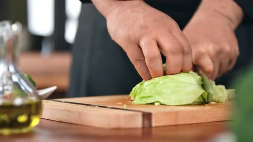 Man Cook Worker Hand Cutting Green Lettuce Leaf on Kitchen Table