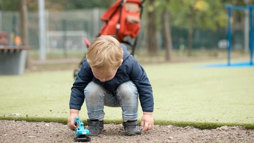 Child Plays with Excavator Toy in Park