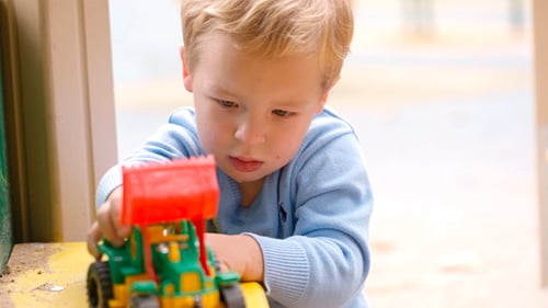 Blond Child Playing with Tractor Toy Outside