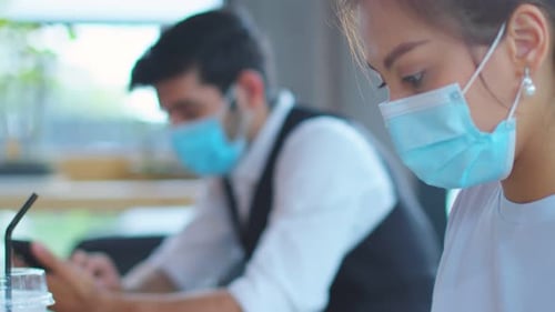People Wearing Masks While Using Cellphones Indoors