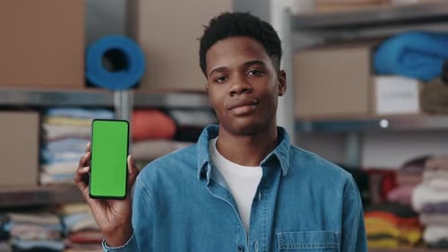 Portrait View of the Multiracial Man Holding Smartphone with Green Mock Up Screen and Showing It to