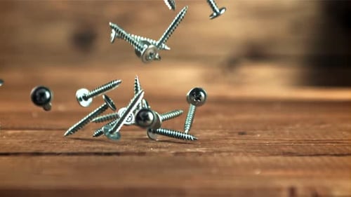 Silver Screws Falling in Slow Motion on Wood