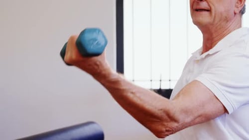 Senior Man Lifting Dumbbell Indoors