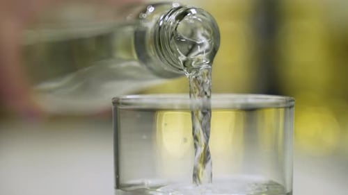 Pouring Clear Liquid into Glass Close Up