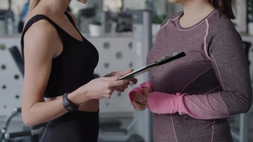 Tilt up view of fitness instructor and woman having a chat. Shot with RED helium camera in 8K