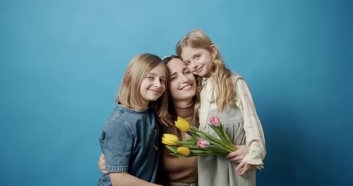 Loving Mother Embracing Her Two Daughters with Flowers