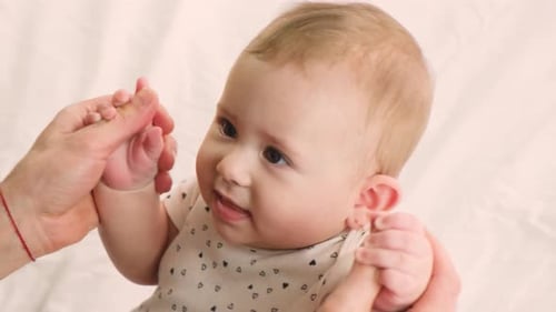 Loving Father Holding Baby's Hands at Home