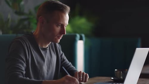 Man Working at Laptop and Writing Notes