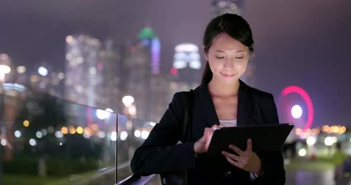 Woman Using Tablet in City at Night