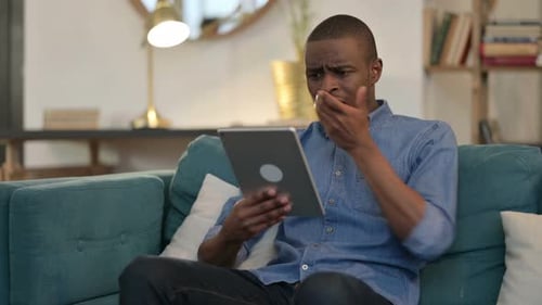 Man Shocked While Using Tablet on Sofa