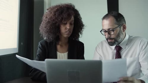 Colleagues Discussing Data at Desk in Office