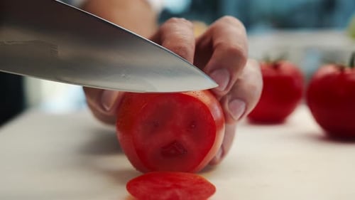 Professional restaurant kitchen, close-up: Chef cuts tomatoes with a knife