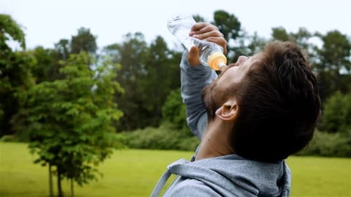 Man Drinking Water in Green Urban Park