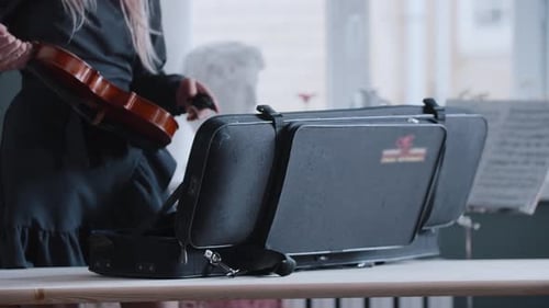 Woman Retrieves Violin from Case Indoors