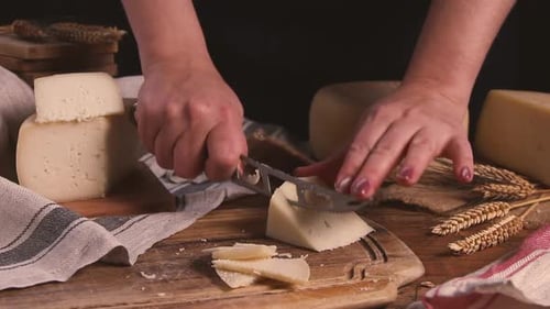 Women cut fresh homemade cheese on a wooden board with a cheese knife close up